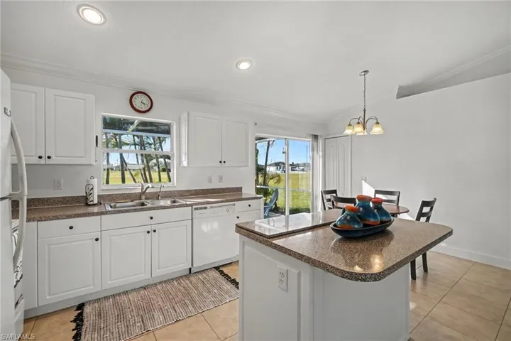 Kitchen featuring white cabinetry, solid surface countertops, a central island, recessed lighting, and tile flooring