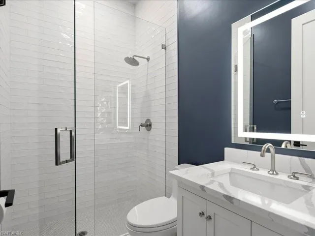 The 4th full bathroom in this ensuite was renovated in 2024 and features a walk-in shower with tile surround, built-in storage nook, and lighted mirror.