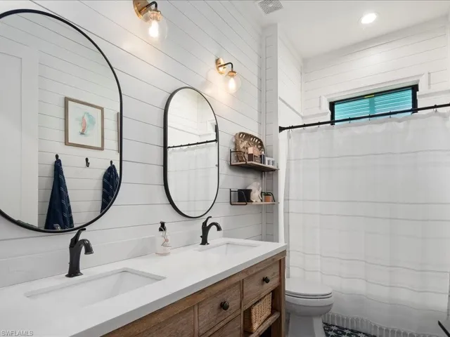 The third full bathroom boasts a double vanity, custom tile features, and shiplap walls, complementing the nautical theme.
