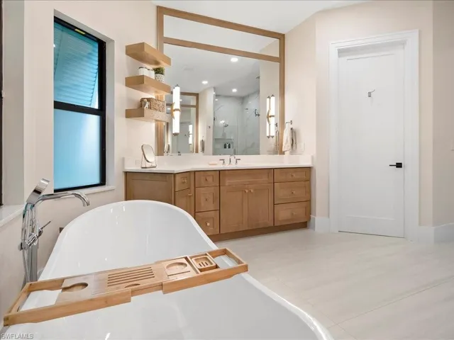 Full bath featuring vanity, a marble finish shower, a freestanding tub, and recessed lighting