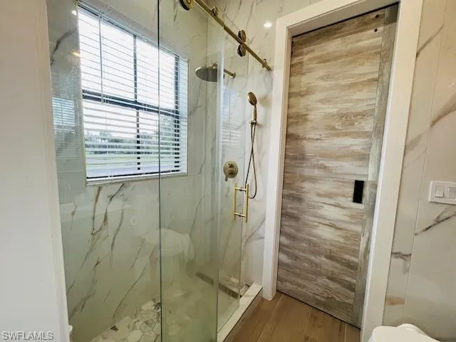 Full bathroom with toilet and a marble finish shower