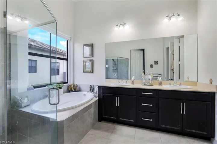 Bathroom with a bath, double vanity, a shower stall, and light tile patterned flooring