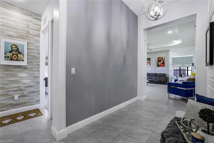 Corridor with light tile patterned floors, a chandelier, and recessed lighting