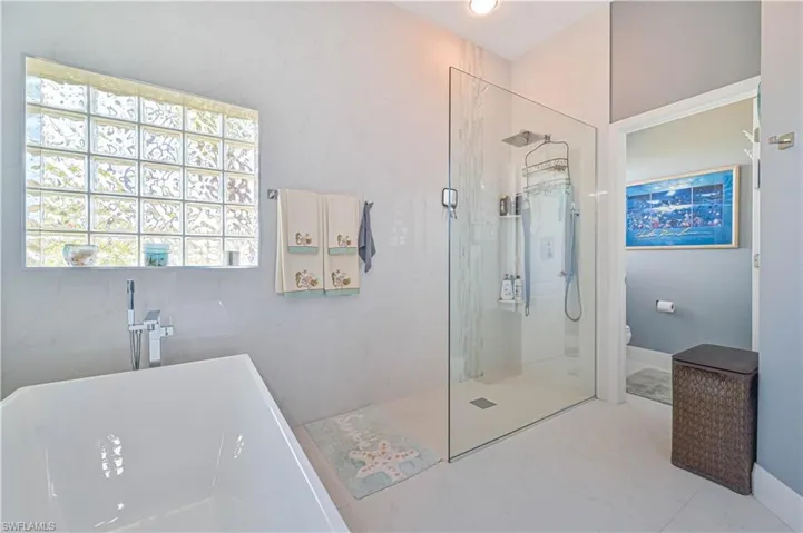 Full bath featuring toilet, a freestanding bath, a marble finish shower, and marble finish floor