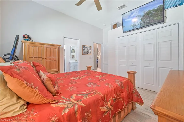 Bedroom with visible vents, a closet, light wood-style floors, high vaulted ceiling, and a ceiling fan