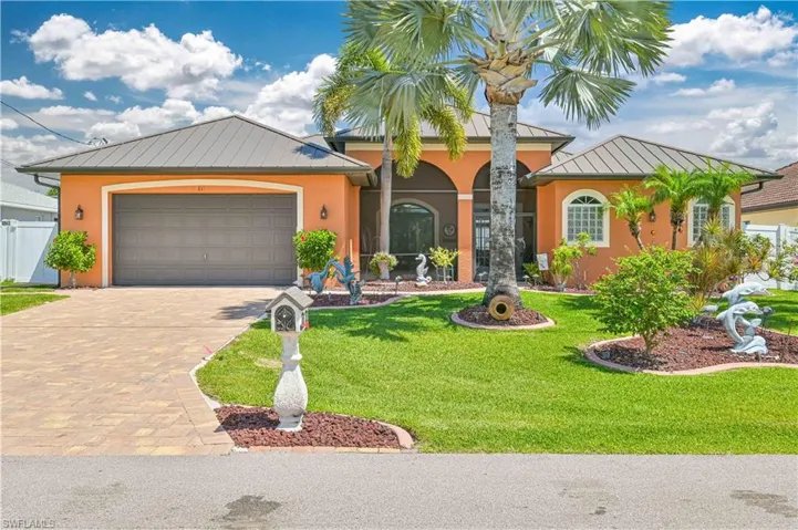 Mediterranean / spanish home featuring a standing seam roof, metal roof, decorative driveway, a front lawn, and stucco siding