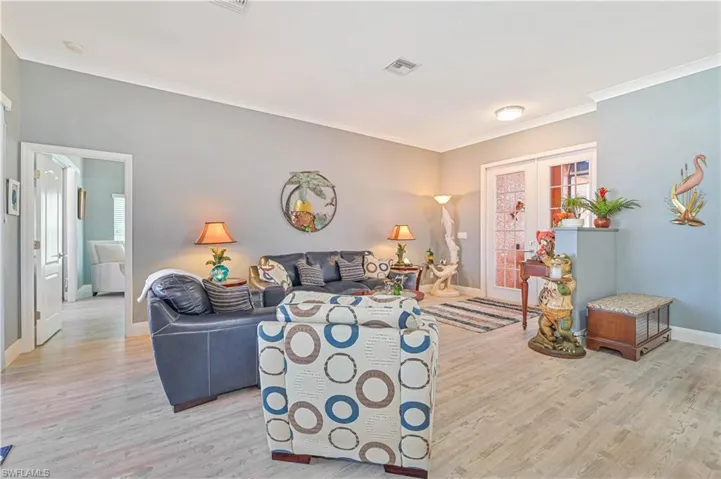 Living room featuring crown molding, baseboards, visible vents, and light wood-style flooring