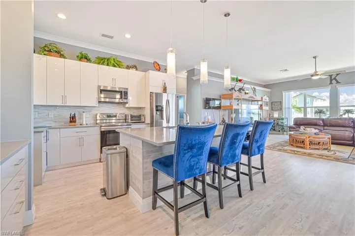 Kitchen featuring crown molding, appliances with stainless steel finishes, a kitchen bar, backsplash, and visible vents