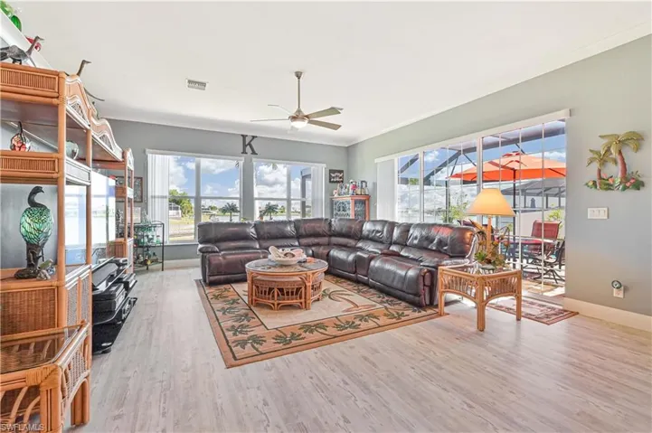 Living room with visible vents, ornamental molding, wood finished floors, baseboards, and ceiling fan