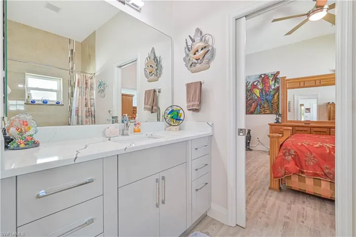 Bathroom with visible vents, vanity, wood finished floors, curtained shower, and a ceiling fan
