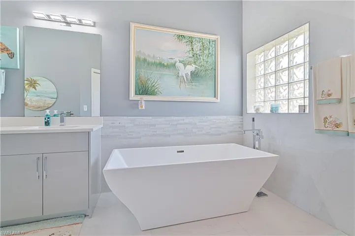 Bathroom with vanity, wainscoting, a freestanding bath, and tile walls