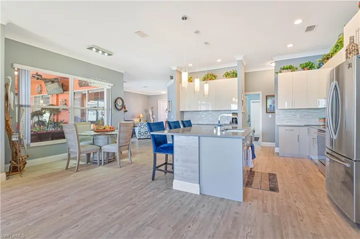 Kitchen with freestanding refrigerator, crown molding, visible vents, and a sink