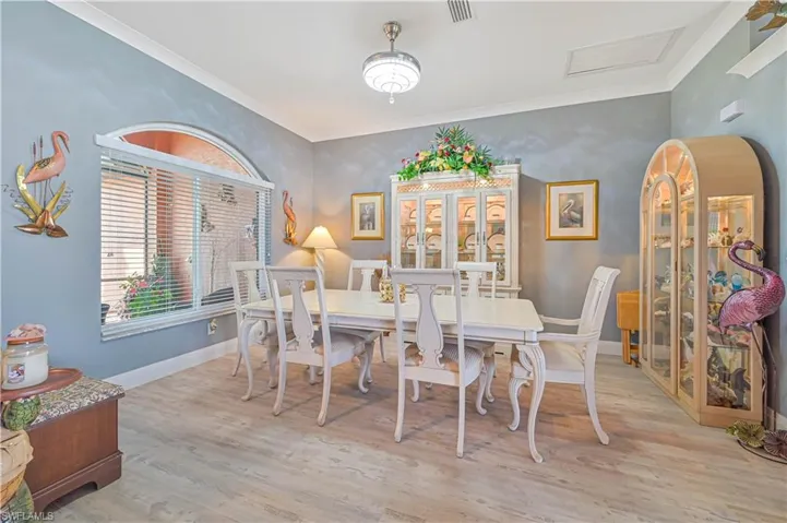 Dining room with visible vents, baseboards, crown molding, and wood finished floors