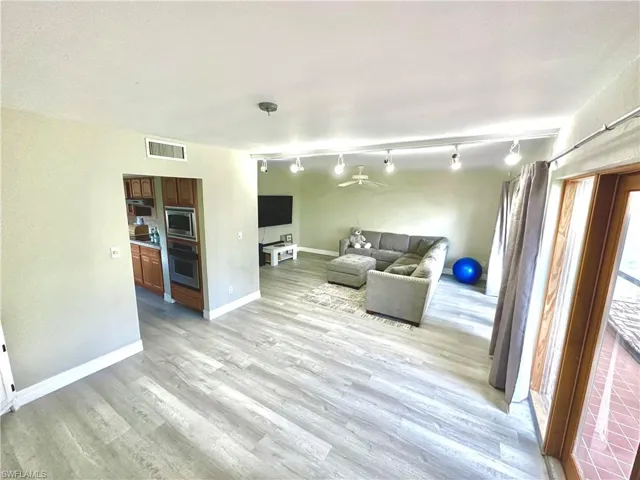 Open-concept living area with wood-finish flooring, track lighting, and a ceiling fan