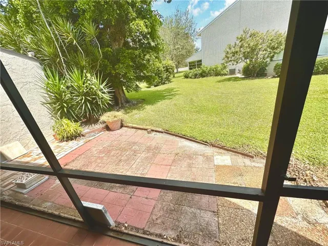 Screened patio featuring terra cotta-toned pavers, an expansive lawn, and mature landscaping