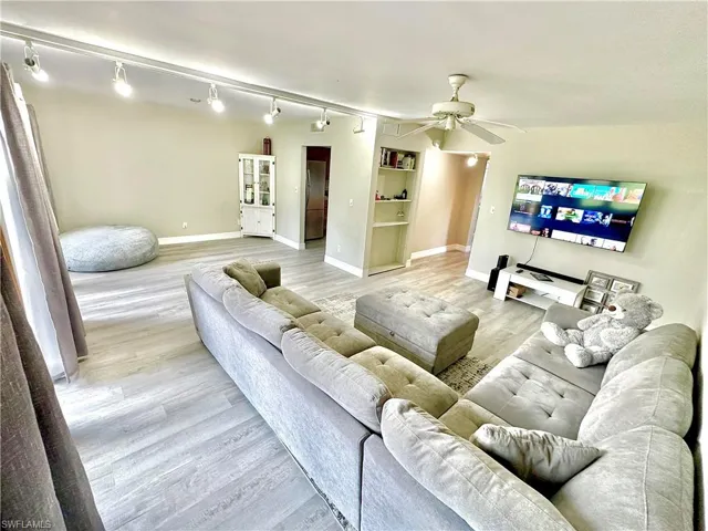 Spacious living area featuring wood-finish flooring, track lighting, and a ceiling fan
