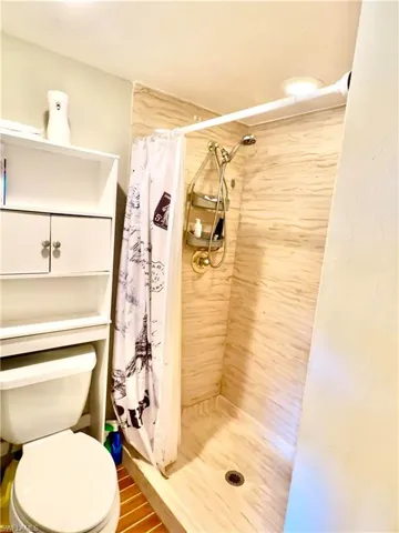 Shower featuring light-toned, horizontally textured tile walls and a matching tile floor