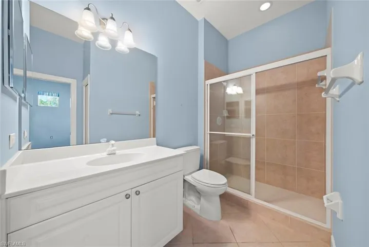 Bathroom with vanity, toilet, a shower stall, and tile patterned flooring