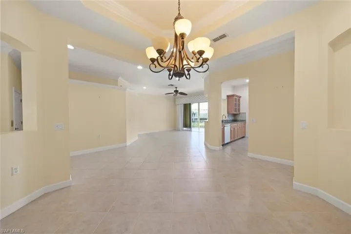 Open dining area with volume ceilings, chandelier and tile floors.