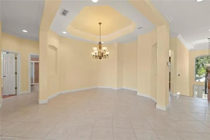 Open dining area with volume ceilings, chandelier and tile floors.
