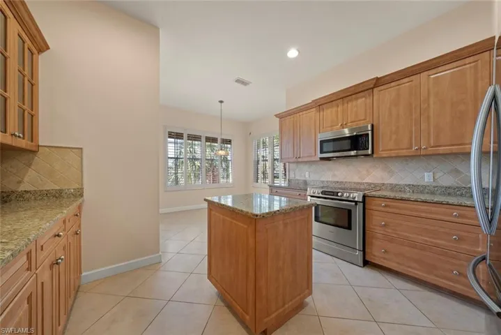 Kitchen featuring an island, granite counter tops and Bosh microwave and stove and tile floors.