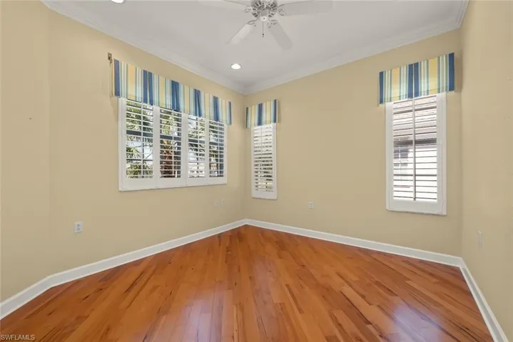 Den with plantation shutters, wood flooring and electric hurricane shutters.