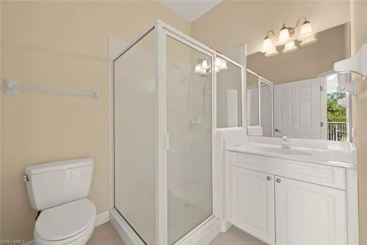 Bathroom with vanity, toilet, a shower stall, and tile patterned flooring