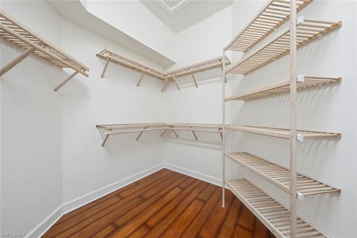 Primary Bedroom Closet with light stone counters and wood flooring