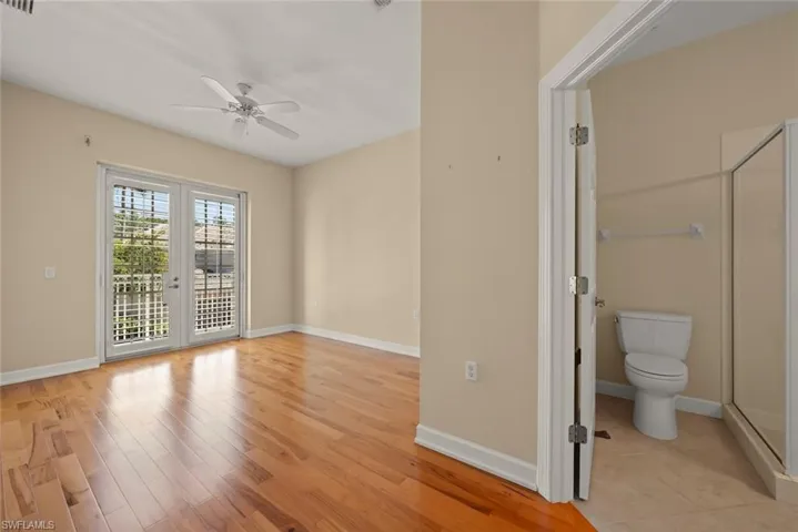 bedroom featuring ensuite bath, hardwood / wood-style flooring, balcony and a closet.