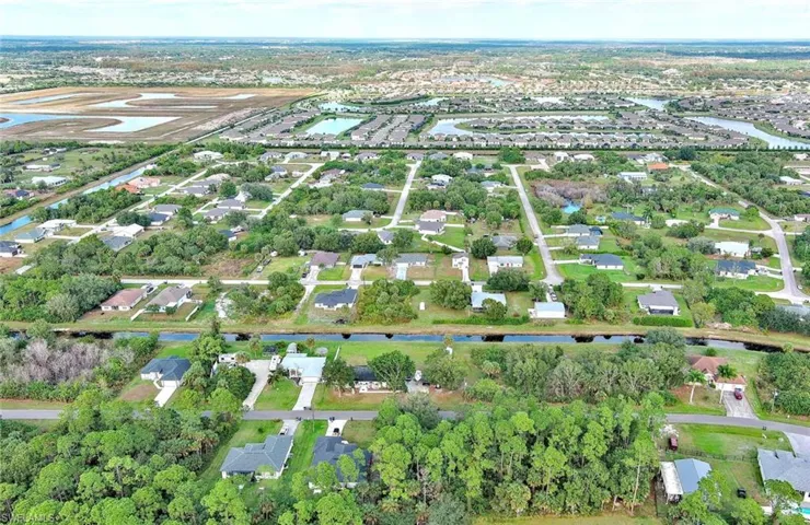 Aerial view of property and surrounding area featuring a nearby body of water and nearby suburban area