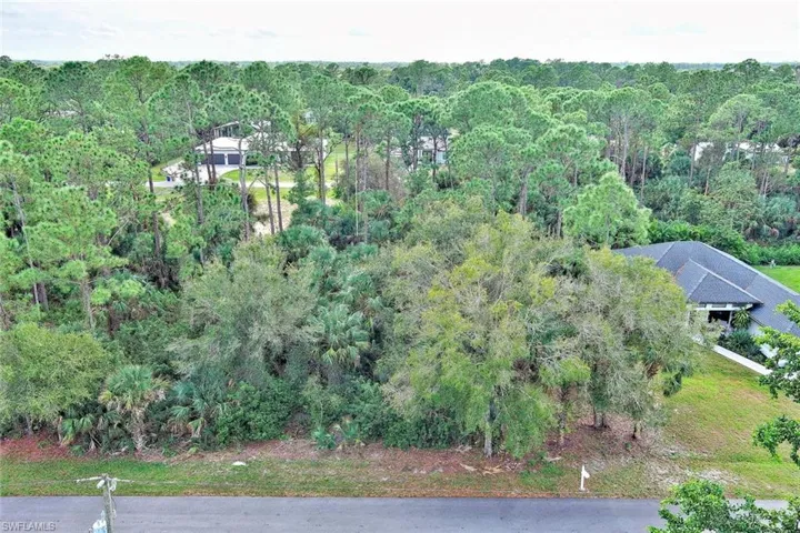Aerial view of property and surrounding area featuring a forest