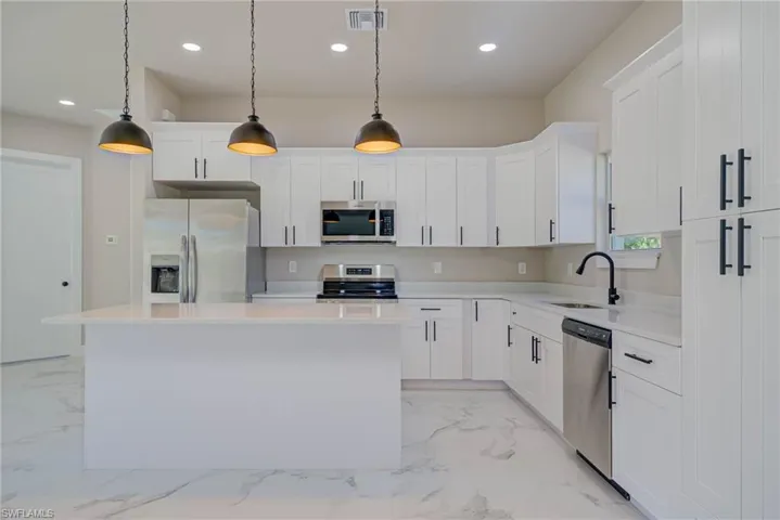 Kitchen with visible vents, marble finish floor, appliances with stainless steel finishes, a sink, and a center island