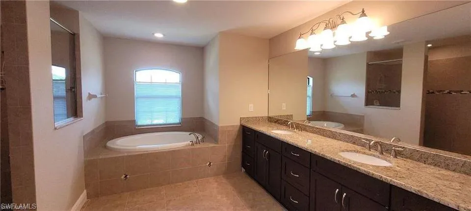 Bathroom featuring plus walk in shower, tile patterned floors, and vanity