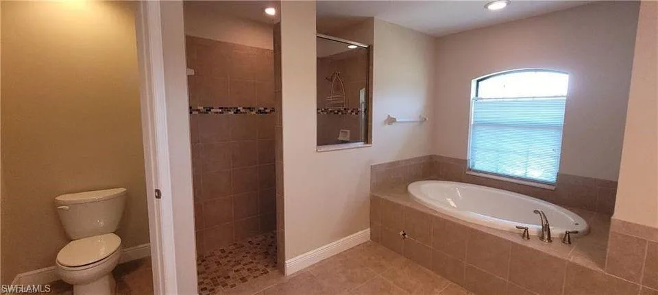 Bathroom featuring separate shower and tub, tile patterned floors, and toilet