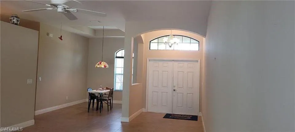 Entryway featuring ceiling fan with notable chandelier, tile patterned floors, and a healthy amount of sunlight