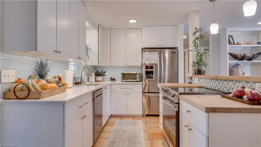Open kitchen with stainless appliances, solid surface counter and tall upper cabinets.