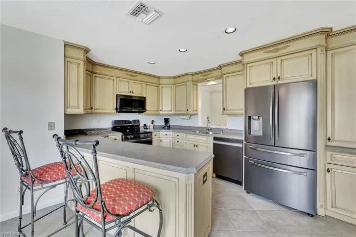 Kitchen featuring appliances with stainless steel finishes, cream cabinetry, recessed lighting, light tile patterned floors, and a sink