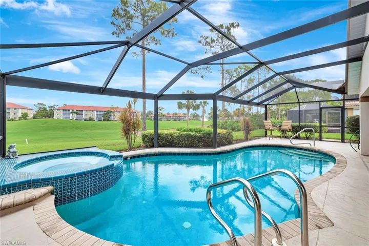 View of swimming pool featuring a lawn, a patio area, a pool with connected hot tub, and glass enclosure