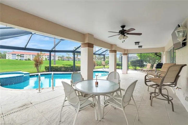 View of pool featuring ceiling fan, a patio area, a pool with connected hot tub, a lanai, and a yard