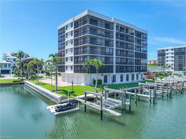 Dock area featuring boat lift, a water view, and a lawn