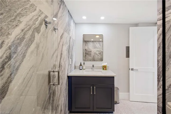 Full bathroom with vanity, a marble finish shower, and recessed lighting