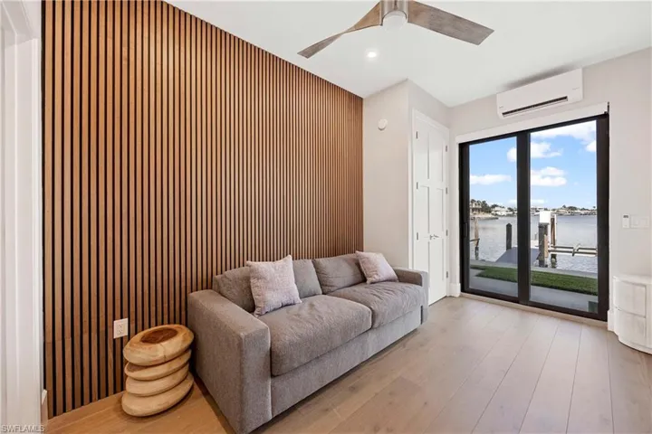 Sitting room featuring a water view, wooden walls, a wall mounted AC, hardwood / wood-style floors, and an accent wall