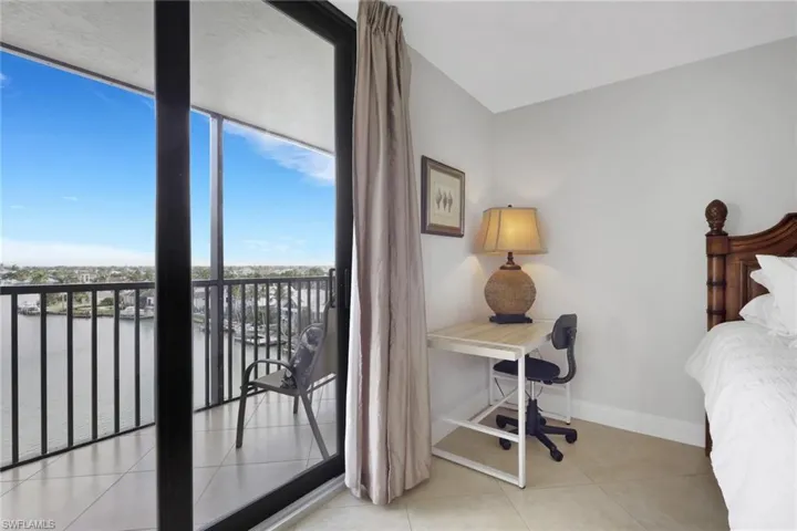Bedroom featuring a water view, an office area, light tile patterned floors, a wall of windows, and access to outside