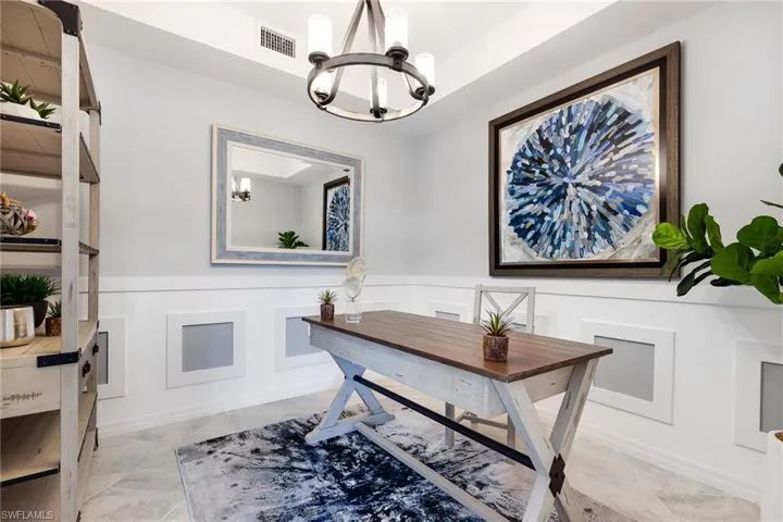 Home office with wainscoting, a decorative wall, and a chandelier
