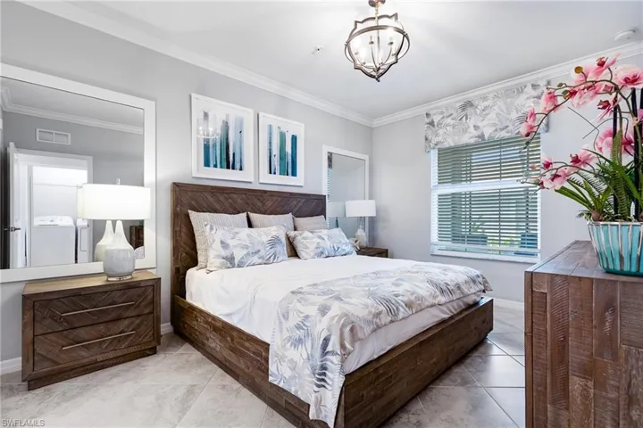 Bedroom with crown molding, a chandelier, and washer and clothes dryer