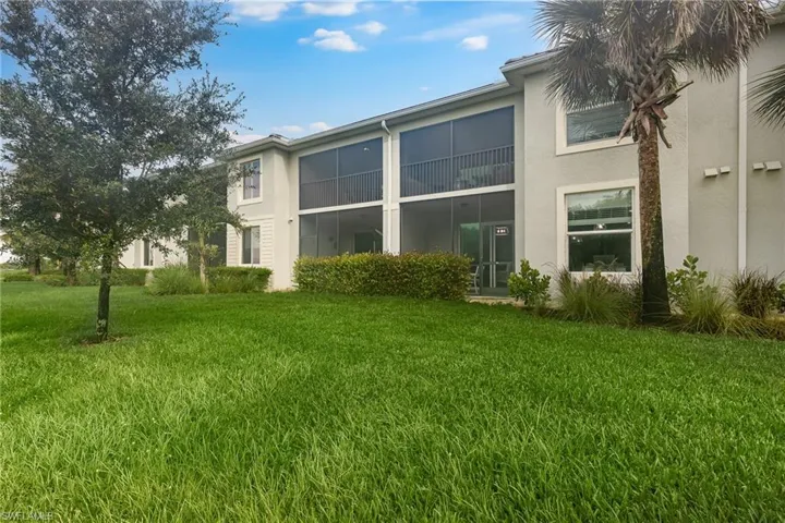 Back of property featuring a lawn, stucco siding, and a balcony