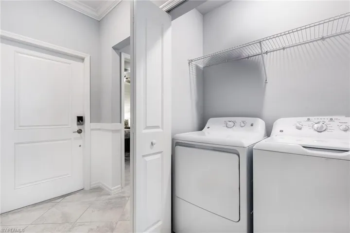 Laundry area with washer and clothes dryer and crown molding