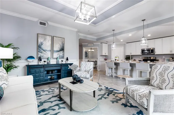 Living area with hanging lights, crown molding, and light tile patterned floors