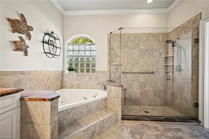 Full bathroom featuring ornamental molding, a jetted tub, a shower stall, and vanity