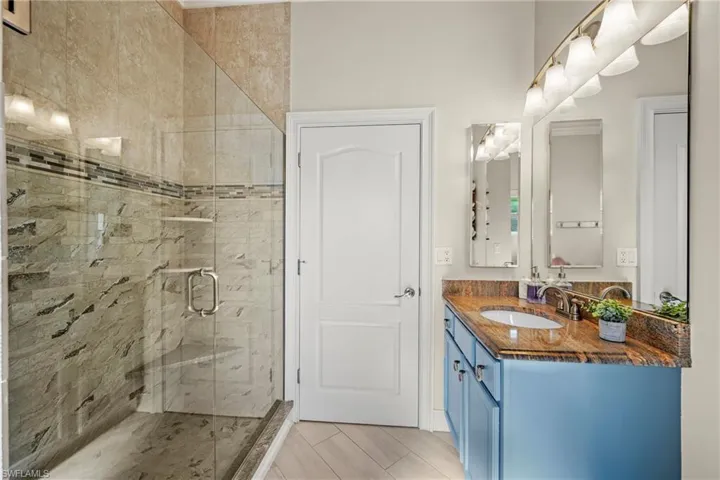 Full bath featuring vanity and a marble finish shower